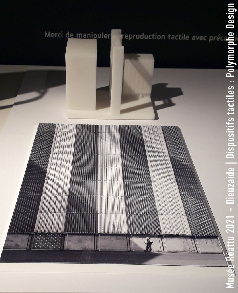 Au premier plan se trouve l'interprétation tactile de l'Autoportait. Derrière se trouve la maquette 3D des bâtiments industriels, l'ombre des bâtiments hors-champs se projetant sur la façade principale, formant de larges diagonales.